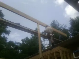 Carpenter setting a ridge beam over a new addition frame — Ice Dam Removal by Roofing Brothers in Brandt