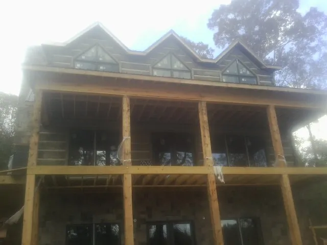 Dormers and porch framing on a large log home under construction — Roof Coating work by our crew in Brandt