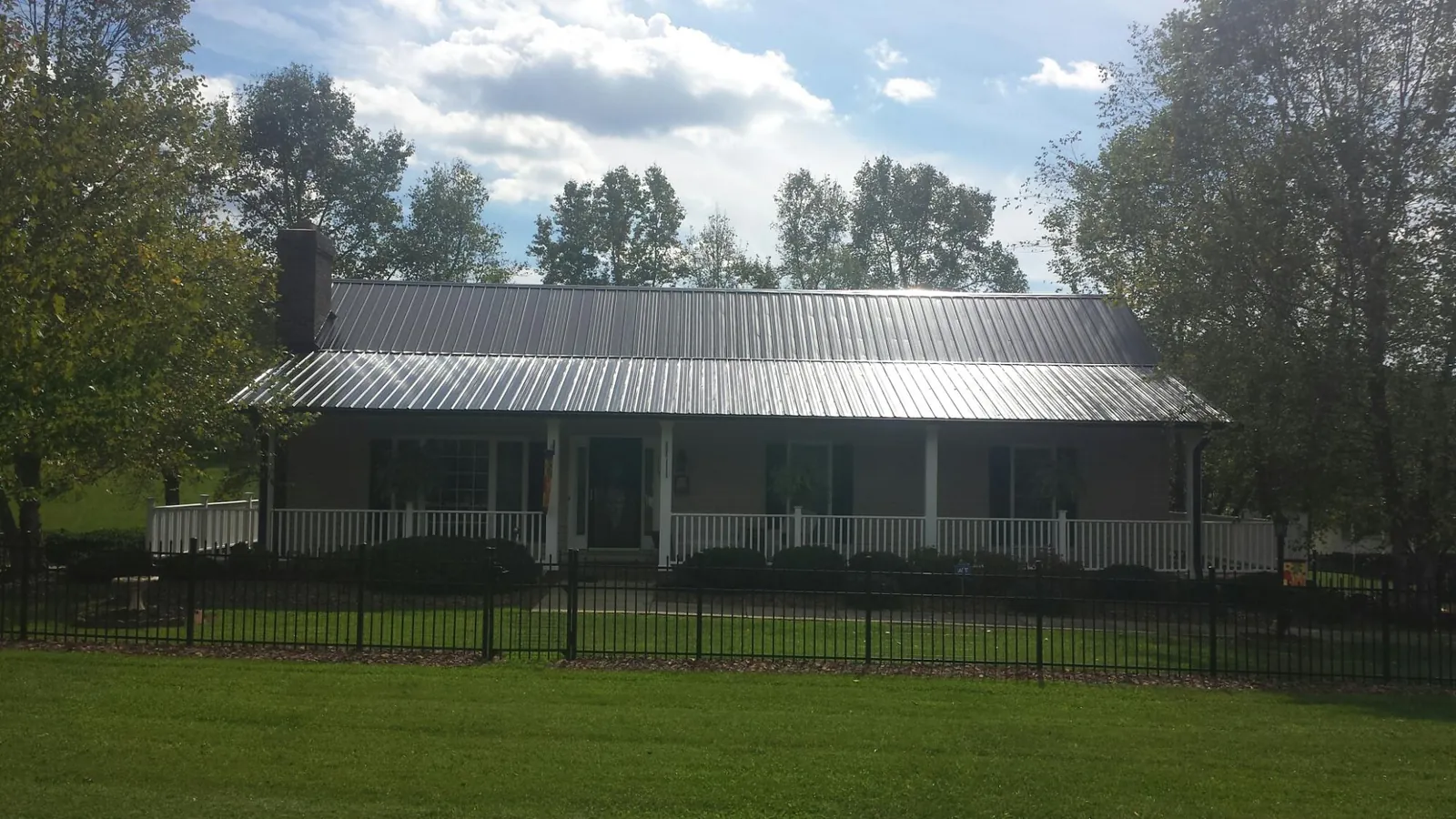 Gray metal roof on a brick ranch with a full width front porch — Gutter Guard Installation work by our crew in Brandt