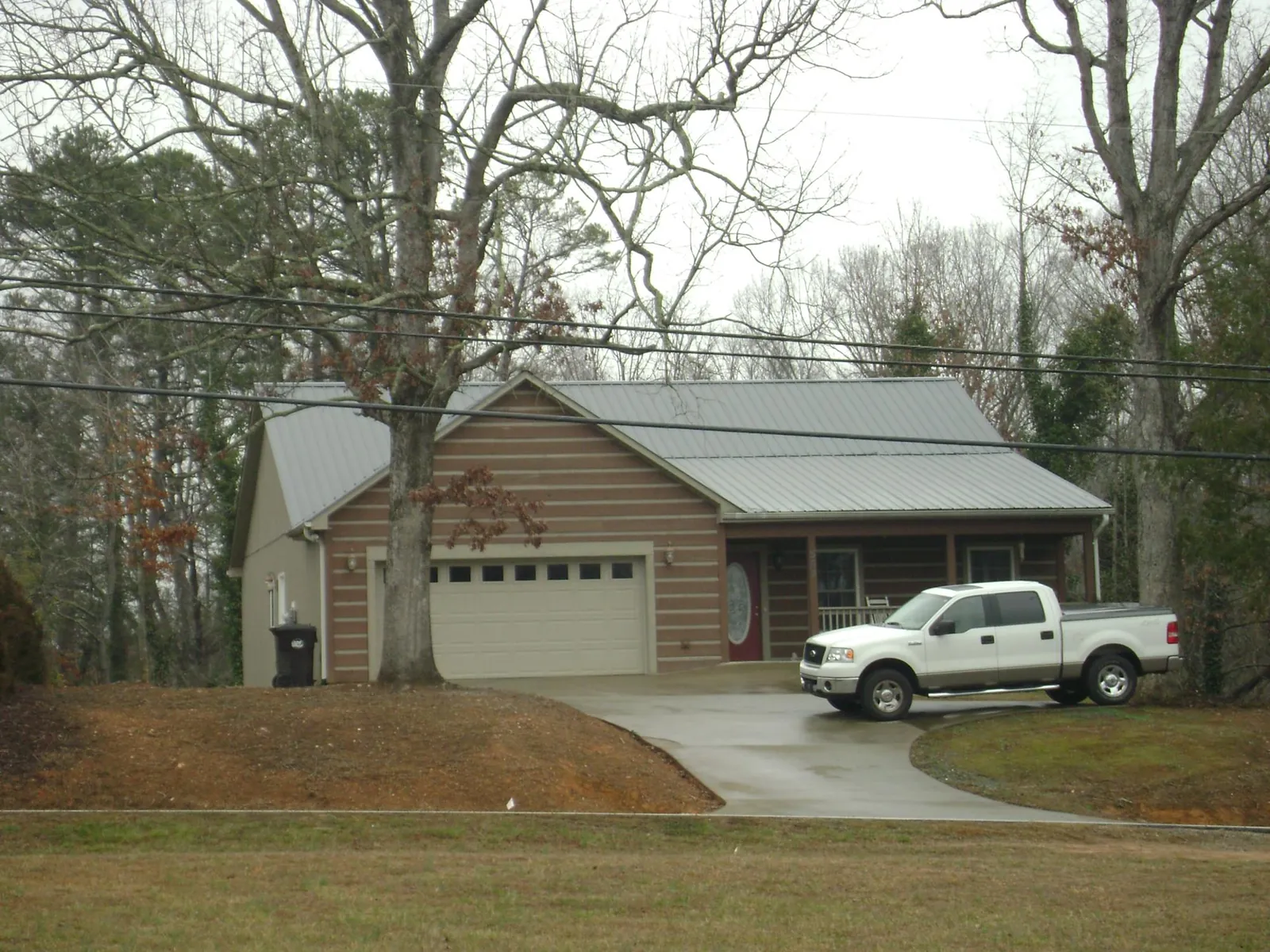 Gray metal roof on a log sided house with an attached two car garage in Brandt
