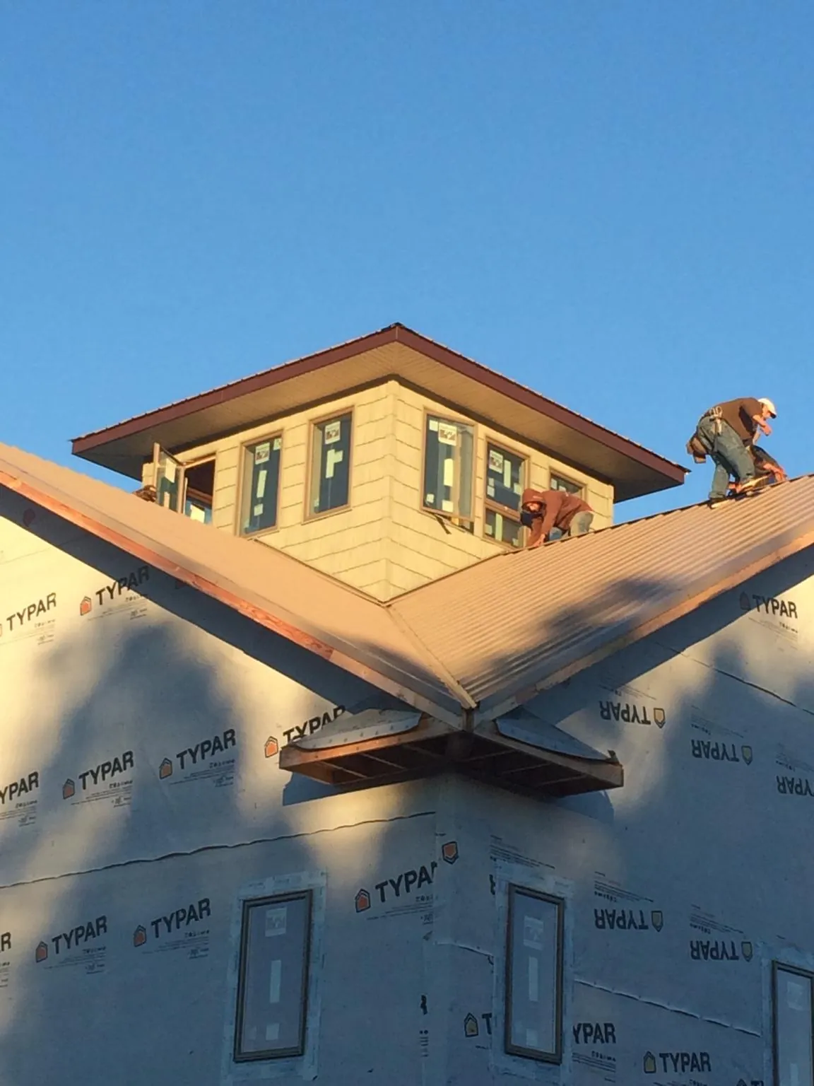 Roofers working around a rooftop cupola on a new metal roof at sunset — Roof Waterproofing in Brandt by Roofing Brothers